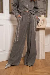 Pantalón denim gris con efecto lavado y detalles de pedrería en el frente, de corte amplio.