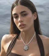 Collar con dije de sol en espiral de acero quirúrgico hipoalergénico, suspendido de un tiento trenzado blanco.