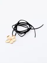 Gargantilla choker con cordón fino de terciopelo negro y dije de flor dorada.