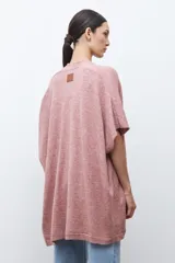 Ruana de tejido de punto color rosa melange, sin mangas y con cuello redondo.