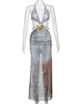 Vestido largo de fiesta con escote halter, espalda descubierta y abertura lateral en la falda. Presenta un top triangular con detalle de abertura en el abdomen y una cadena dorada con dije de concha que rodea la cintura. El estampado es abstracto en tonos grises y marrones.