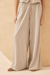 Pantalón palazzo color beige de lino, con cintura elástica y cordón ajustable.