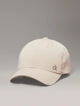Gorra de béisbol color beige claro, confeccionada en sarga de algodón orgánico, con visera curva y herraje metálico con el monograma 'ck' en el frente.