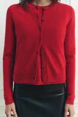 Chaqueta de punto liso color rojo, confeccionada en 100% lana. Tiene cuello redondo, manga larga, terminaciones en rib y cierre frontal con botones.
