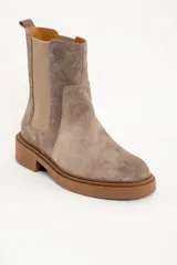 Bota Chelsea de gamuza color visón, con elásticos laterales y suela de goma color caramelo.