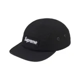 Gorro tipo camp cap color negro con logo de la marca Supreme en etiqueta blanca cosida en el frente. Tiene ojales metálicos en los laterales.