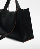 Bolso tipo tote grande color marrón, con doble asa de mano y correa larga extraíble. Interior con dos compartimentos y bolsillo central con cierre.