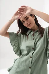 Camisa larga verde con botones frontales y detalles de volantes en las mangas, de estilo atemporal.