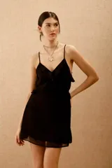 Vestido corto negro con escote en V, espalda descubierta y volados. Confeccionado en viscosa georgette, con breteles finitos que se atan en la espalda y ajuste elástico en la cintura.