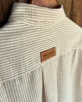 Camisa a rayas verticales, con cuello clásico y cierre frontal con botones.