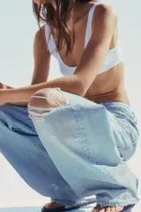 Pantalón de jean celeste claro, corte baggy, tiro medio, largo hasta el tobillo y con roturas grandes en ambas piernas.