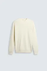 Jersey color crema de punto perlado, con cuello redondo, manga larga y corte regular fit.