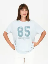 Remera celeste con estampa frontal con el número 85 y texto "Padel Team Malibu CA".