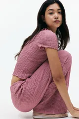 Pantalón recto color rosado, de punto con efecto arrugado, con elástico y cordón ajustable en la cintura.