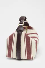 Bolso de mano tipo city, confeccionado en tejido con estampado de rayas verticales en tonos crudo y bordó. Tiene doble correa de hombro extraíble en contraste de tejidos, detalles metálicos y cierre mediante cremallera.
