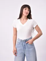 Remera blanca de punto con cuello en V y mangas cortas con volados.