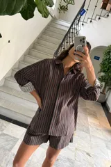 Conjunto de camisa y short a rayas verticales marrones y negras. La camisa es de manga larga con puños que pueden doblarse, mostrando un estampado a cuadros en el interior.