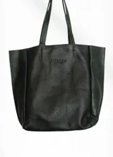 Bolso negro tipo tote bag de cuero con asas cortas.