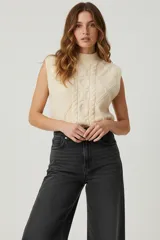 Chaleco sin mangas color beige, con cuello alto y tejido de ochos.