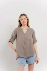 Camisa azul de lino con escote en V abotonado, bolsillo frontal y mangas 3/4 con trabilla.