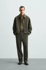 Pantalón verde oscuro de corte recto, con cintura elástica, bolsillos laterales y un bolsillo trasero. Cierre frontal con cremallera y botón.