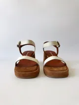 Sandalias de cuero color crudo, con dos tiras anchas sobre el empeine, pulsera al tobillo con hebilla y taco cuadrado de madera.