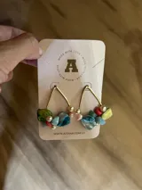 Aros colgantes con forma triangular dorada, con piedras de colores y perlas.
