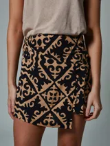 Falda short negra con estampado geométrico en color beige, con detalle de lazo lateral.