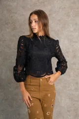Blusa negra de encaje cluny con mangas abullonadas tres cuartos y cuello alto festoneado.