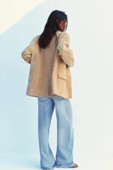 Blazer color camel confeccionada en piel de ante 100%. Diseño clásico con cuello solapa, escote pico, manga larga, bolsillos con solapa en delantero, forro interior combinado, bajo con abertura en espalda y cierre frontal con botones.