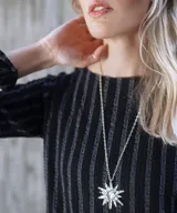 Collar con cadena fina negra y dije de estrella plateada con incrustaciones de strass.