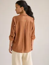 Camisa color marrón de lino y viscosa, de corte clásico, con cuello camisero, cierre frontal con botones, mangas largas con puños abotonados y dos bolsillos de parche en el pecho.