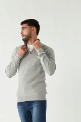 Sweater gris de punto con medio cierre, cuello alto y logo bordado en el pecho.