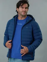 Campera acolchada azul con capucha, cierre frontal con cremallera y bolsillos laterales con cremallera. Diseño ligero y funcional. Marca Calvin Klein.