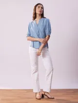 Blusa celeste de lyocell, con cuello a la base, escote en V y botones. Delantera con bolsillo y manga corta con terminación en punto smock.
