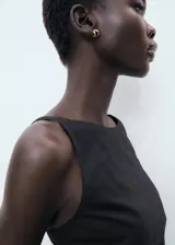 Vestido corto negro de corte ajustado, sin mangas y con cuello redondo. Presenta detalle drapeado en la falda.