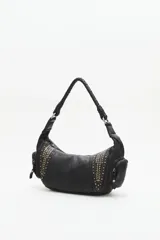 Cartera tipo hobo de cuero vacuno color negro, con apliques de tachas doradas y plateadas. Tiene un asa corta trenzada y dos bolsillos externos con cierre.