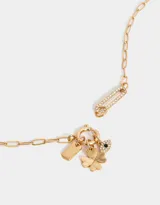 Collar corto dorado con cadena de eslabones y multidijes: candado con corazones dorados, dedal plateado, mano negra, cuentas de cristal, pez plateado, borla de cordones verdes y dije de luna plateada.