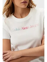 Remera blanca de algodón con cuello redondo y logo "Calvin Klein Jeans" estampado en degradé de rosa a celeste. Corte slim fit y mangas cortas.