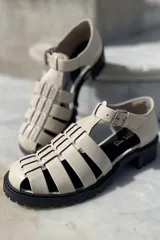 Sandalias de cuero color cobre con diseño de tiras entrecruzadas, hebilla lateral y suela track color negro.