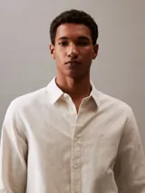 Camisa de manga larga color blanco hueso, confeccionada en lino y algodón. Tiene cuello clásico, cierre con botones y un bolsillo en el pecho.
