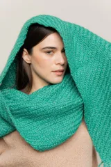 Ruana verde esmeralda de tejido de punto con flecos en el borde inferior.