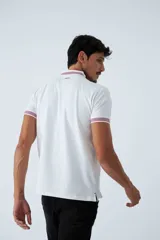 Remera cuello polo blanca de piqué, corte regular, manga corta, logo estampado y terminaciones a contratono en cuello y mangas con rayas rojas, grises y azules.