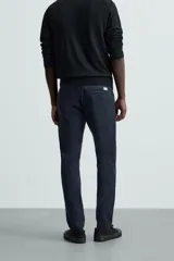 Pantalón chino color beige, corte skinny fit, confeccionado en tejido con mezcla de algodón y elasticidad. Cuenta con bolsillos frontales y traseros. Cierre frontal con cremallera y botón.