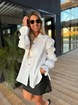 Camisa color verde lima confeccionada en lino, de corte holgado, con cuello camisero, mangas largas abullonadas con puños elásticos y cierre frontal con botones.