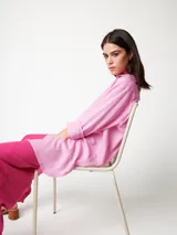 Camisa oversized color rosado, con largo por debajo de la cadera, mangas largas y bolsillo con detalle bordado.