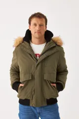 Campera Wrangler de hombre, modelo Teddy, color verde militar con capucha desmontable con borde de piel sintética, cierre frontal con cremallera y botones a presión, bolsillos laterales con solapa y puños y cintura acanalados en negro.