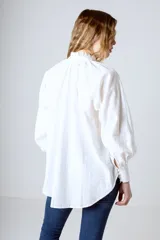 Blusa celeste con rayas verticales blancas, cuello mao y mangas largas abullonadas con puños elásticos.