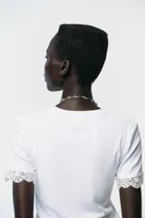 Camiseta blanca de algodón con cuello redondo y mangas cortas con detalle de encaje negro.