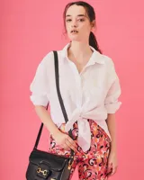 Bandolera color beige con textura símil reptil, cierre con broche metálico dorado y correa larga regulable.